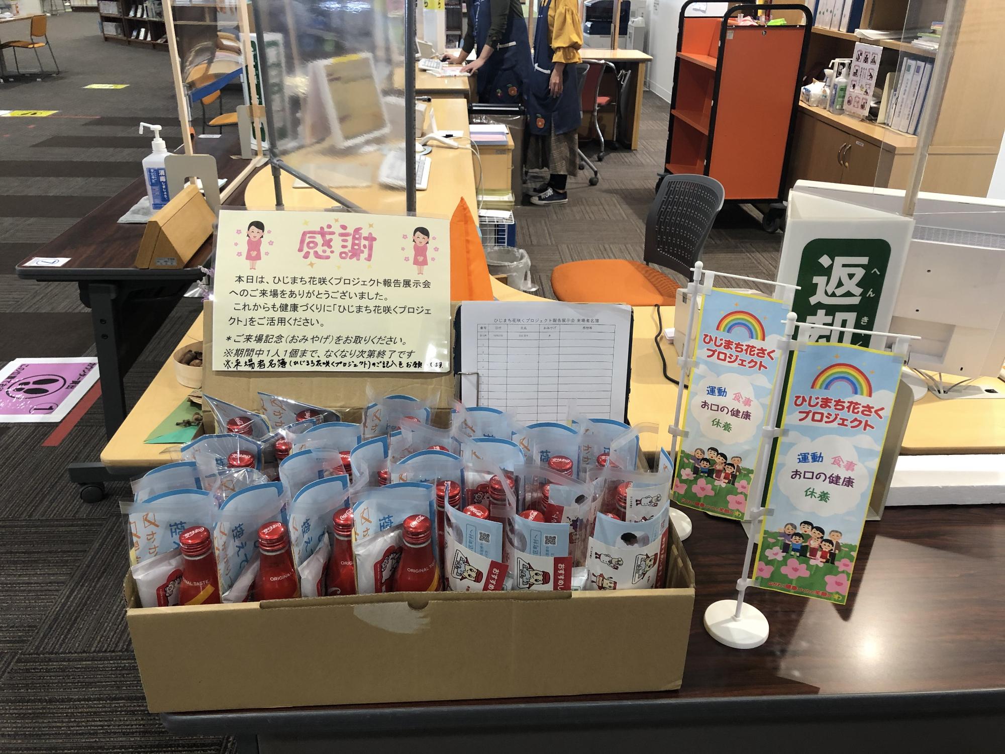 出口の机の上にひじまち花咲くプロジェクトの小さな旗やお土産などが置かれている写真