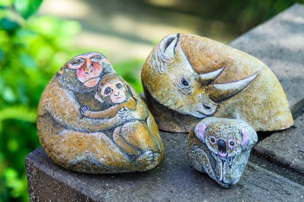 丸みのある石の表面を動物に見立て、サルの親子やサイ、コアラが描かれた石の写真