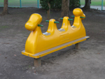 黄色い本体に3人分の座るところと緑の持ち手がついているスプリング遊具の写真