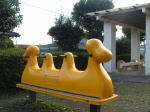 3人乗りの黄色の乗り物に、緑の持ち手がついているスプリング遊具の写真