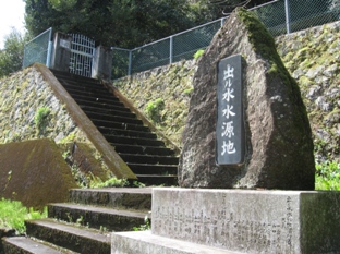 出ル水水源地と書かれた石碑があり、その奥に階段があり、上にはフェンスが立っている写真
