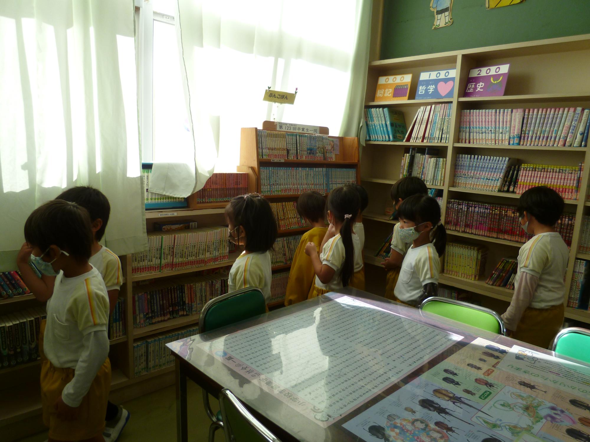 図書室の中で8人の子どもが読む本を選んでいる様子の写真