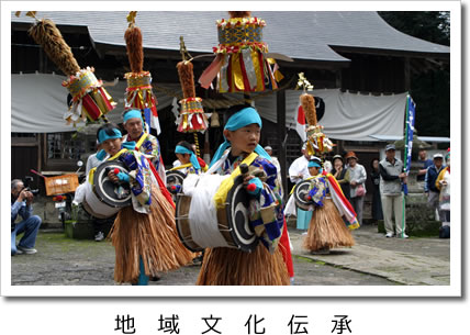 地域文化伝承：青いハチマキを頭に締め、背中に纏が付けられ、太鼓を持って踊りを披露している子ども達の写真