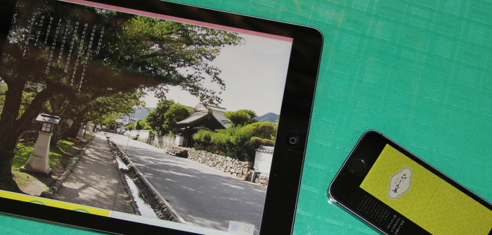 左側に日出町の街並みの写真が映ったタブレット、右側にひじん本の表紙が映ったスマートフォンが置いてある写真