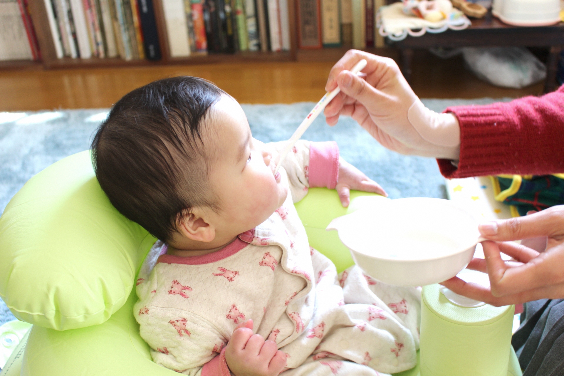 椅子に座ってご飯を食べさせてもらっている赤ちゃんの写真